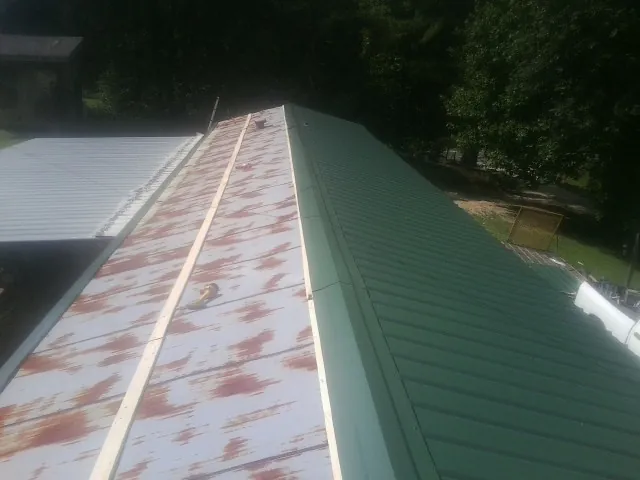 Old rusted panels beside newly installed green metal roofing — Wind Damage Roof Repair by Roofing Brothers in East Greenwich