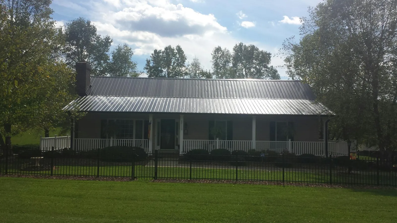 Gray metal roof on a brick ranch with a full width front porch — Gutter Guard Installation work by our crew in East Greenwich