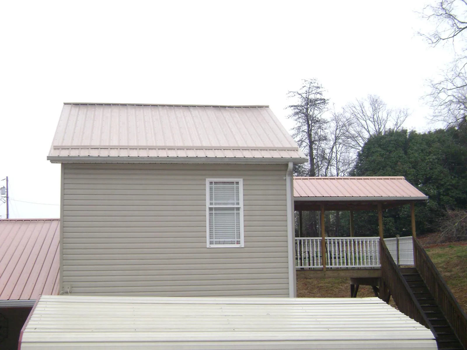 Tan metal roofs on a two story addition and attached porch, from a Roof Replacement job in East Greenwich