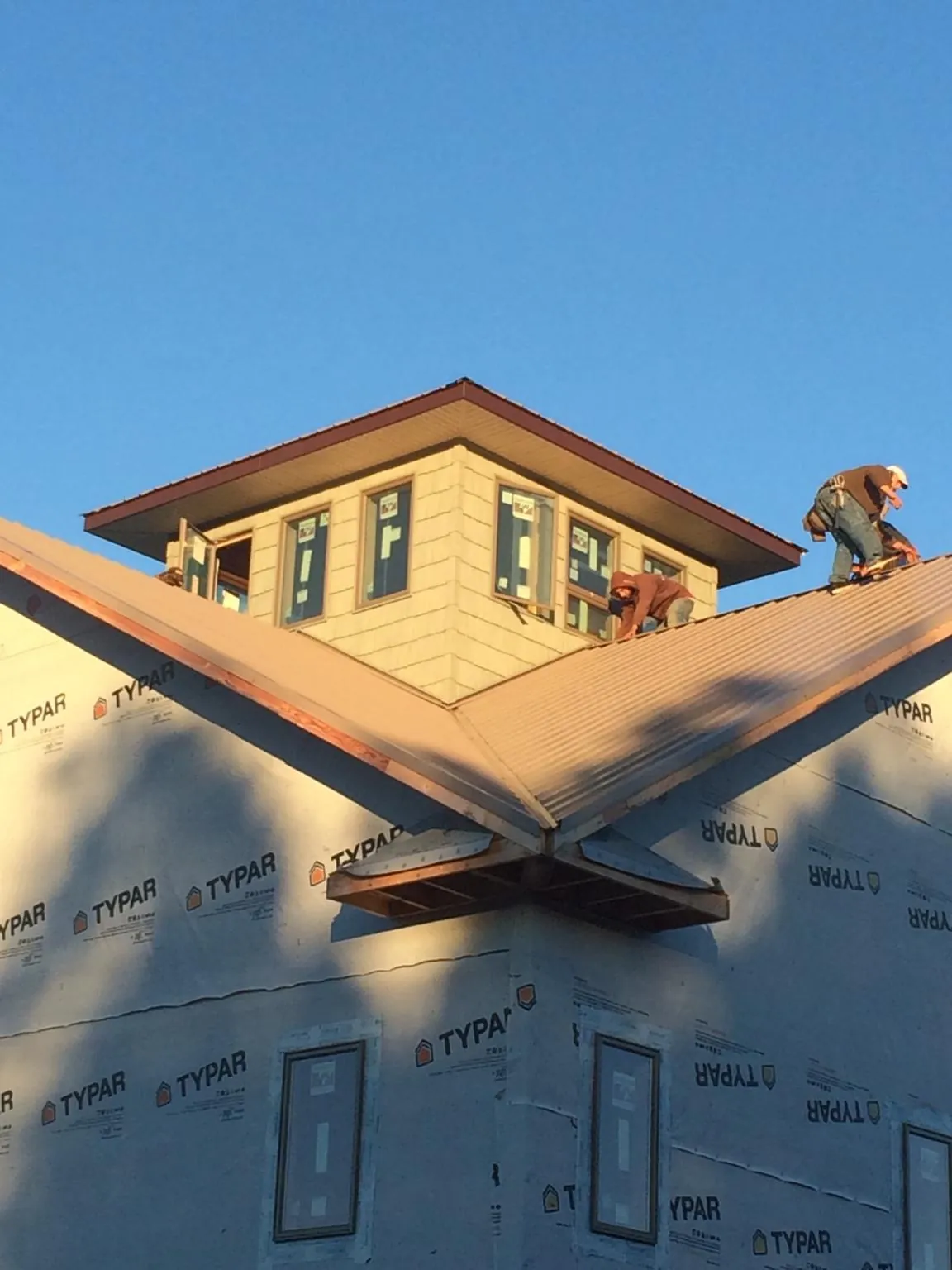Roofers working around a rooftop cupola on a new metal roof at sunset — Roof Waterproofing in East Greenwich by Roofing Brothers